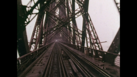 Alia Syed, Points of Departure: A dramatic film still of a muddy red railway bridge made of steel.