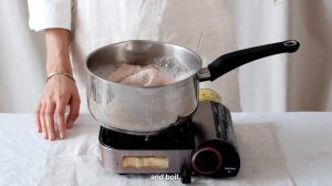 A silver saucepan containing steaming water, organic materials and fabric