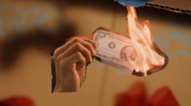 Close up of cut out image of hand holding a dollar on fire
