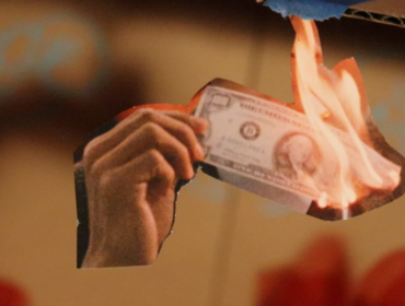 Close up of cut out image of hand holding a dollar on fire